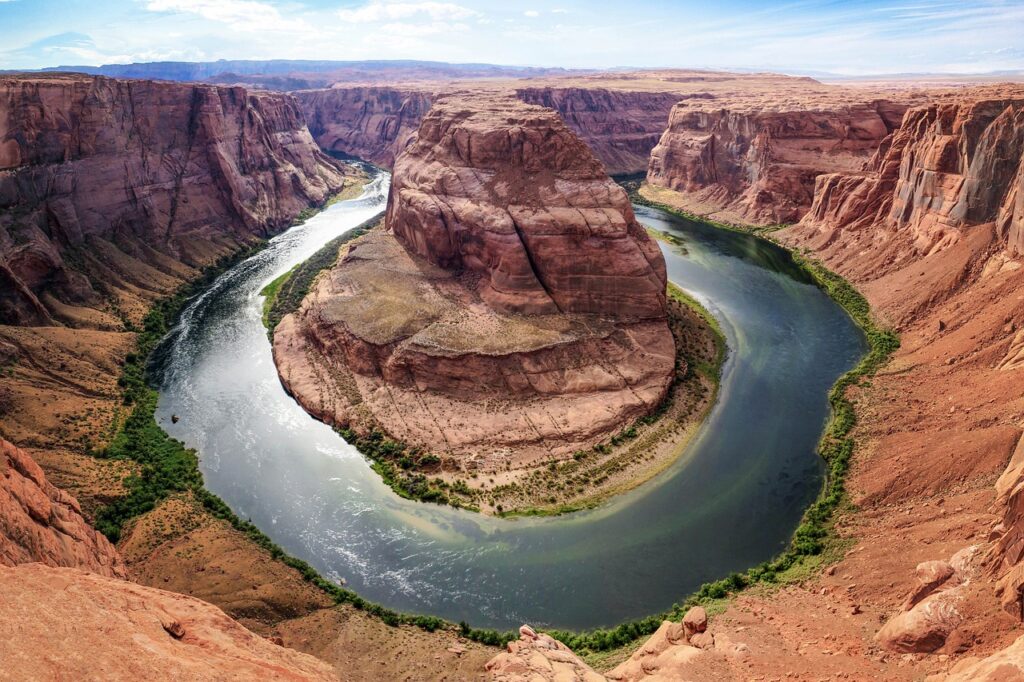 Panoramic view of the Grand Canyon National Park in Arizona with layered red rock formations and the Colorado River below.