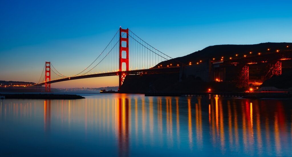 Iconic view of the Golden Gate Bridge in San Francisco with blue sky and city skyline in the background book your Vacation Packages for That call us now 8662904747.