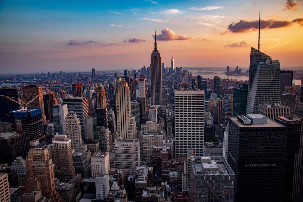 Skyline of New York City featuring the Empire State Building, Times Square lights, and Central Park greenery.